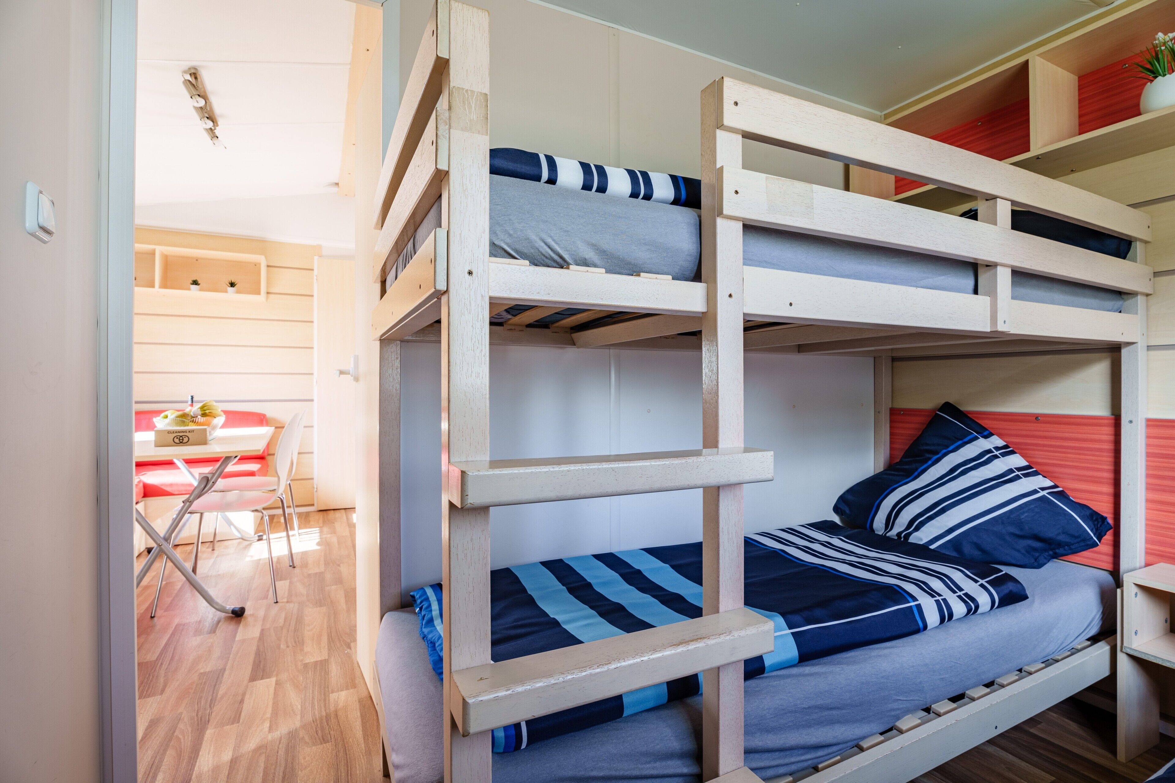 A bunk bed with two levels, a wooden desk, and a red chair in the background.