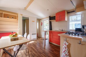 Una cocina con una mesa de madera, sillas, una estufa a gas y armarios rojos.