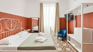Una camera d'albergo con un letto, una sedia blu, un armadio e uno specchio.