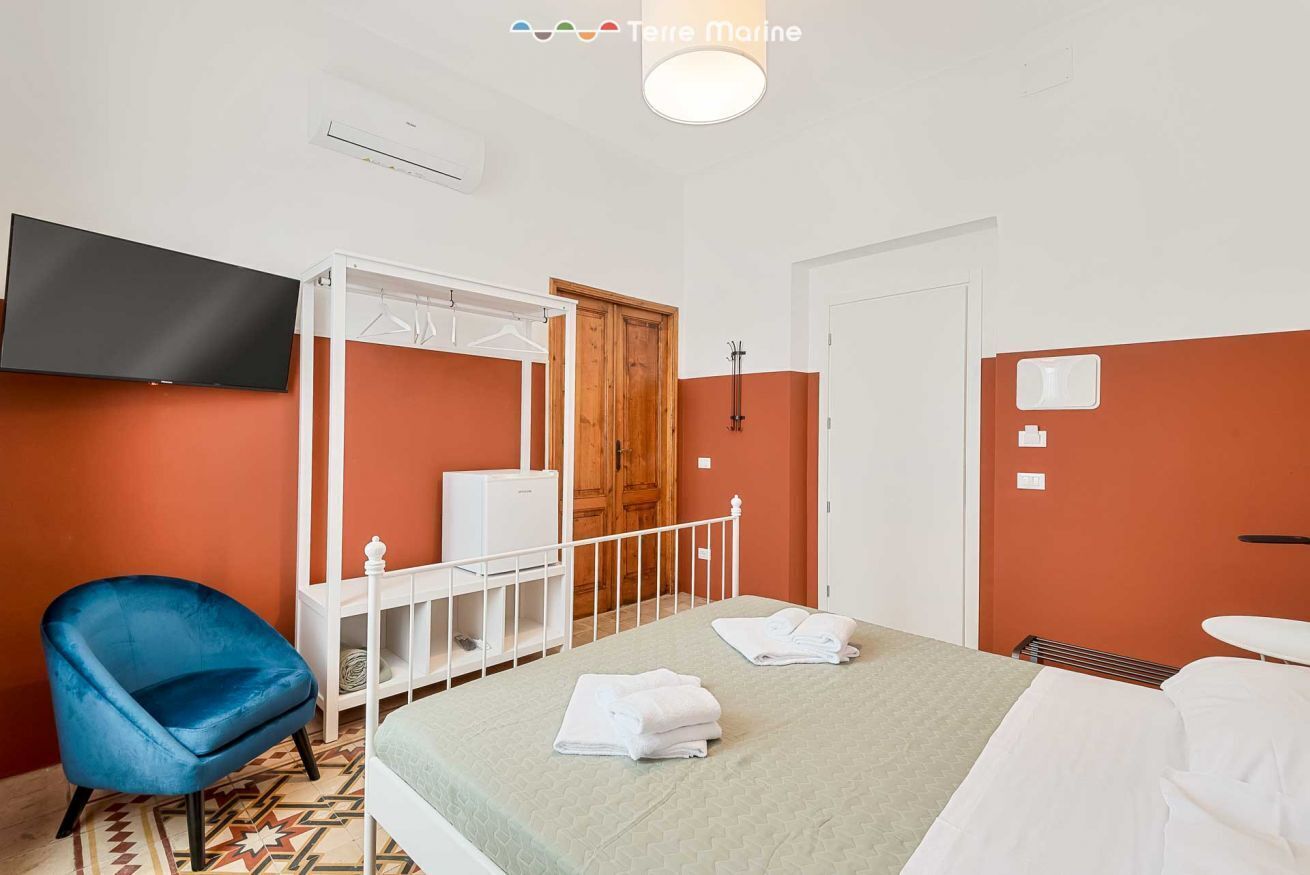Une chambre d’hôtel avec un lit, une chaise bleue, une télévision et une armoire.