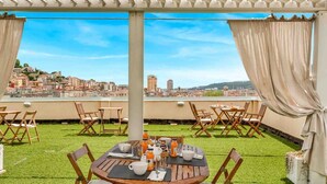Una terrazza sul tetto con tavoli e sedie, vista sulla città e una struttura pergolata.