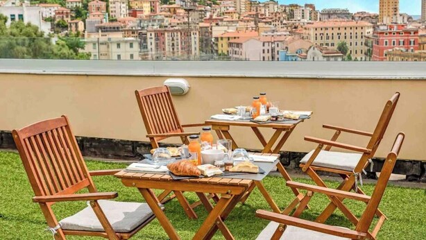 Una terrazza sul tetto con un tavolo apparecchiato per la colazione, circondata da sedie di legno.