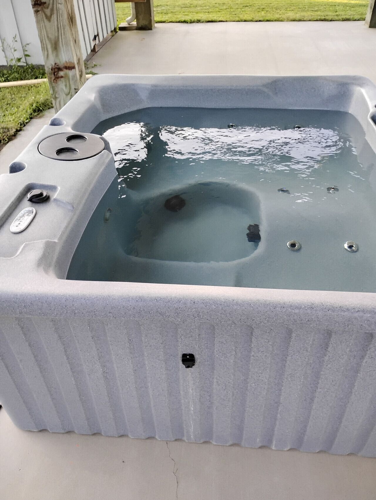 Una bañera de hidromasaje con asiento integrado, panel de control y tapón de desagüe.
