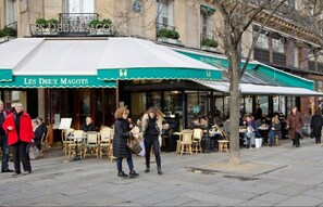 An outdoor cafe with tables and chairs, a green awning, and people walking by. - LOCATED ON THE WALKING DISTANCE FROM FAMOUS CAFÉ DE FLORE & LES DEUX MAGOTS (Paris)