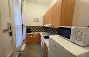 A compact kitchen with wooden cabinets, a microwave, and a coffee maker. - LOCATED ON THE WALKING DISTANCE FROM FAMOUS CAFÉ DE FLORE & LES DEUX MAGOTS (Paris)