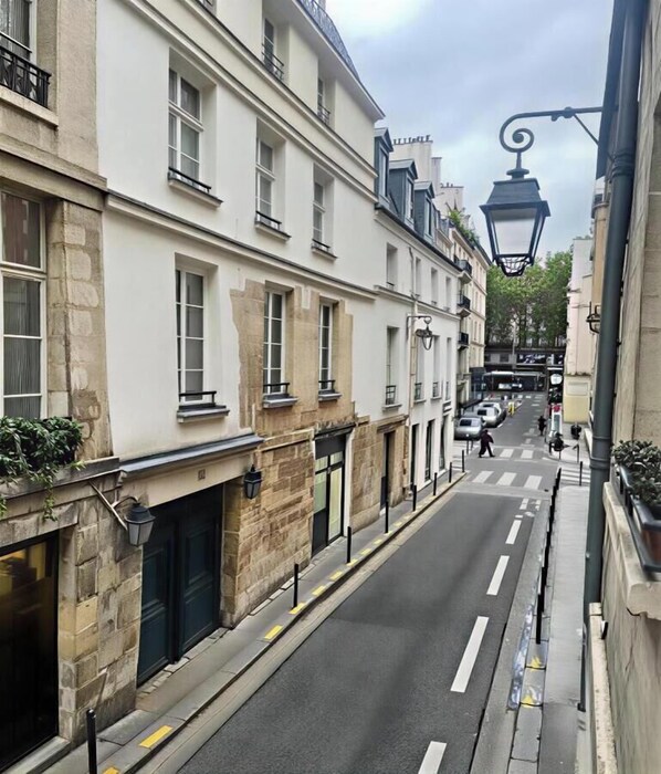 A narrow street lined with historic buildings, featuring stone facades, large windows, and a street lamp. - LOCATED ON THE WALKING DISTANCE FROM FAMOUS CAFÉ DE FLORE & LES DEUX MAGOTS (Paris)