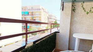 Een balkon met uitzicht op omliggende gebouwen, een witte tafel en een kleine tuin.