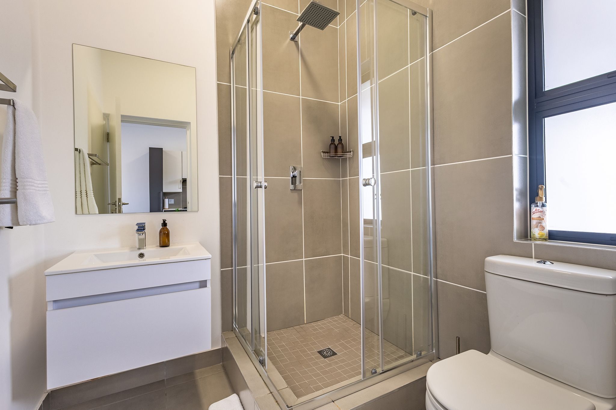 A modern bathroom with a glass-enclosed shower, a white sink, and a toilet.