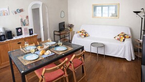 A dining area with a table set for two, a sofa, and a small side table. - Chateau Walk One Bedroom (Fontainebleau)