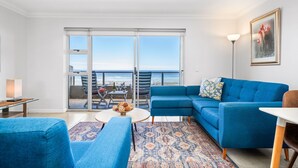 Ein modernes Wohnzimmer mit einem blauen Sofa, einem runden Couchtisch und einem gemusterten Teppich.