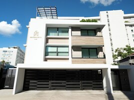 Un edificio moderno de varios pisos con acceso a un garaje, ventanas amplias y un jardín en la azotea.
