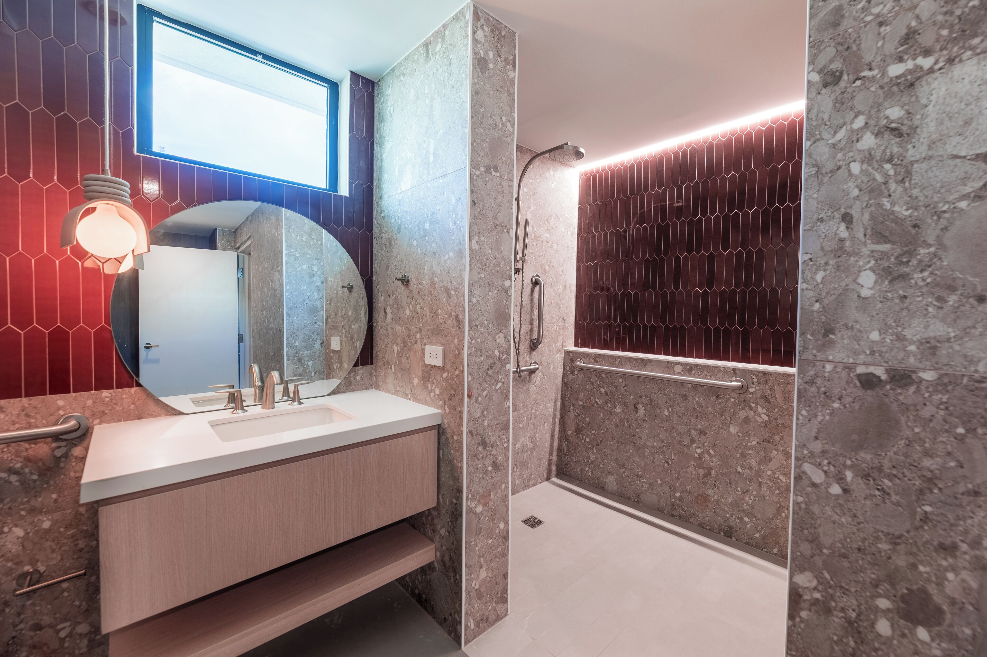A modern bathroom with a large mirror, a sink with a vanity, a shower with a glass door, and a unique hexagonal tile pattern on the walls.