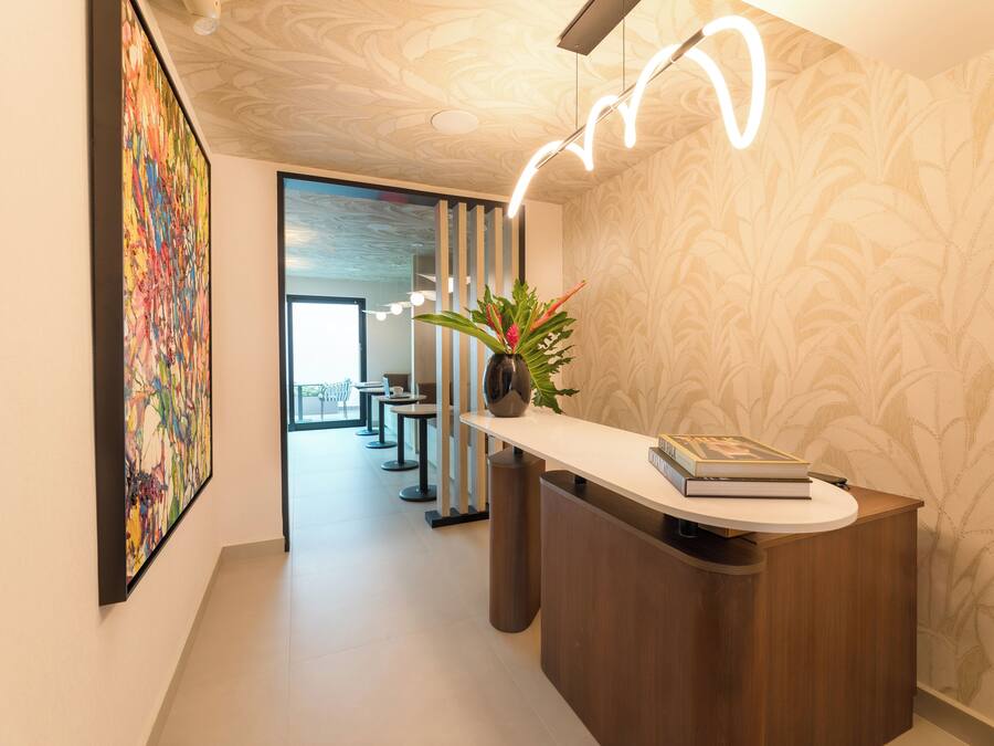 A modern reception area with a wooden reception desk, a colorful abstract painting, and a potted plant.