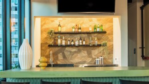 A bar area with a green countertop, black bar stools, and a wall-mounted TV above the bar. - Magdalena 1163 (San Juan)