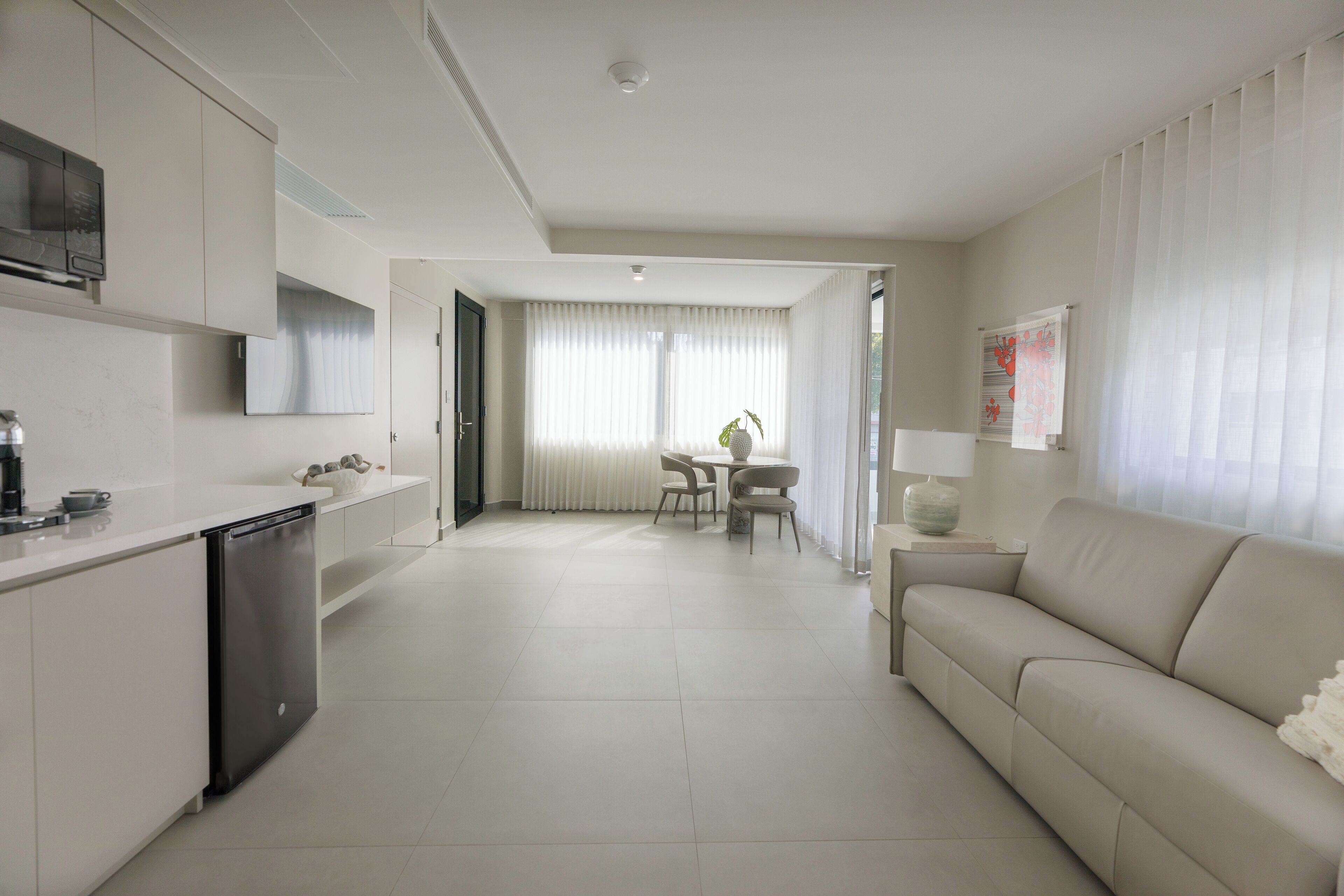 A modern kitchen with white cabinetry, a dishwasher, and a dining area with a table and chairs.
