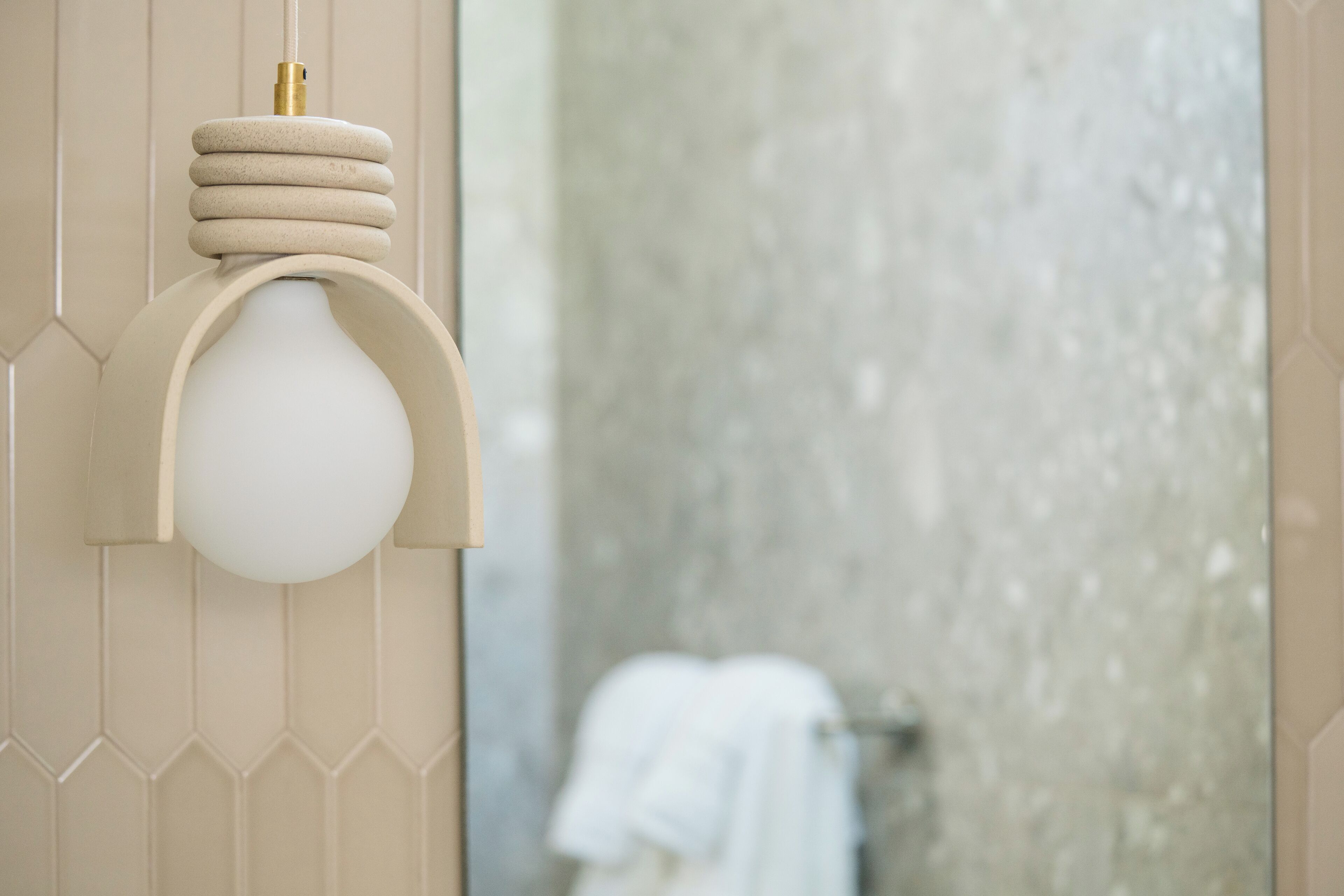 Un baño con una lámpara moderna y un perchero para toallas.