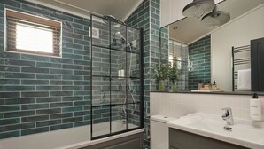 A bathroom with a glass shower enclosure, a white toilet, and a vanity with a mirror. - Wansfell, Whitbarrow (Penrith)