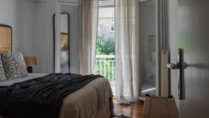 Una camera da letto con un letto, un comodino, una lampada e vista su un balcone.