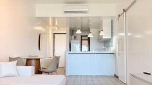 A modern hotel room with a bed, a small dining table, a kitchen area, and a separate living space. - Ocean View of Recreio Beach Lc103 (Rio de Janeiro)