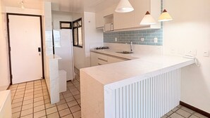 A modern kitchen with a central island, white cabinetry, and a tiled backsplash. - Ocean View of Recreio Beach Lc103 (Rio de Janeiro)