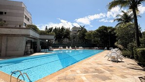 A swimming pool with a tiled deck, lounge chairs, and palm trees. - Ocean View of Recreio Beach Lc103 (Rio de Janeiro)
