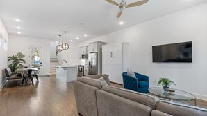 A modern living room with a sofa, a coffee table, and a TV mounted on the wall. - King-bed home near East Nashville with easy access to local attractions (Nashville)