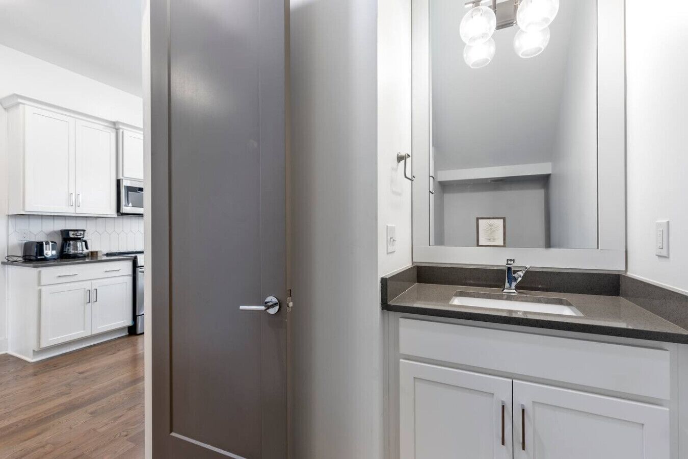 A modern kitchen with white cabinets, a microwave, and a coffee maker.
