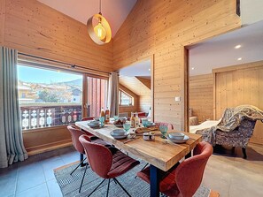 Ein Essbereich mit Holztisch, roten Stühlen und Blick ins Freie.