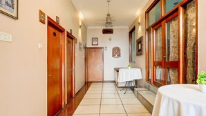 Un corridoio con porte in legno, una ventola a soffitto e un tavolo con una pianta.