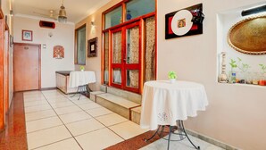 Un'hall d'albergo con pavimento piastrellato, una reception, una scala e una parete con opere d'arte incorniciate e uno specchio decorativo.