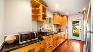 A kitchen with wooden cabinets, a microwave, a sink, and a refrigerator. - Mins To Beach W/ Jacuzzi, Large Yard,Parking & AC! (Oceanside)