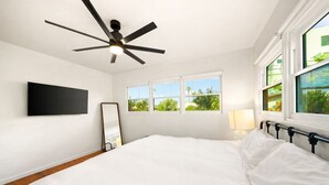A bedroom with a bed, a ceiling fan, a TV, windows, and a view of greenery. - Mins To Beach W/ Jacuzzi, Large Yard,Parking & AC! (Oceanside)