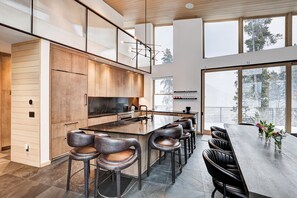 A modern kitchen with a large island, bar stools, and a dining table with chairs.