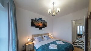 Camera da letto con un letto, lampade ai comodini, un lampadario, un quadro e un pavimento a scacchi.