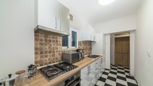 Una cucina moderna con pavimento a scacchi, elettrodomestici in acciaio inossidabile e piastrelle decorative sulla parete.