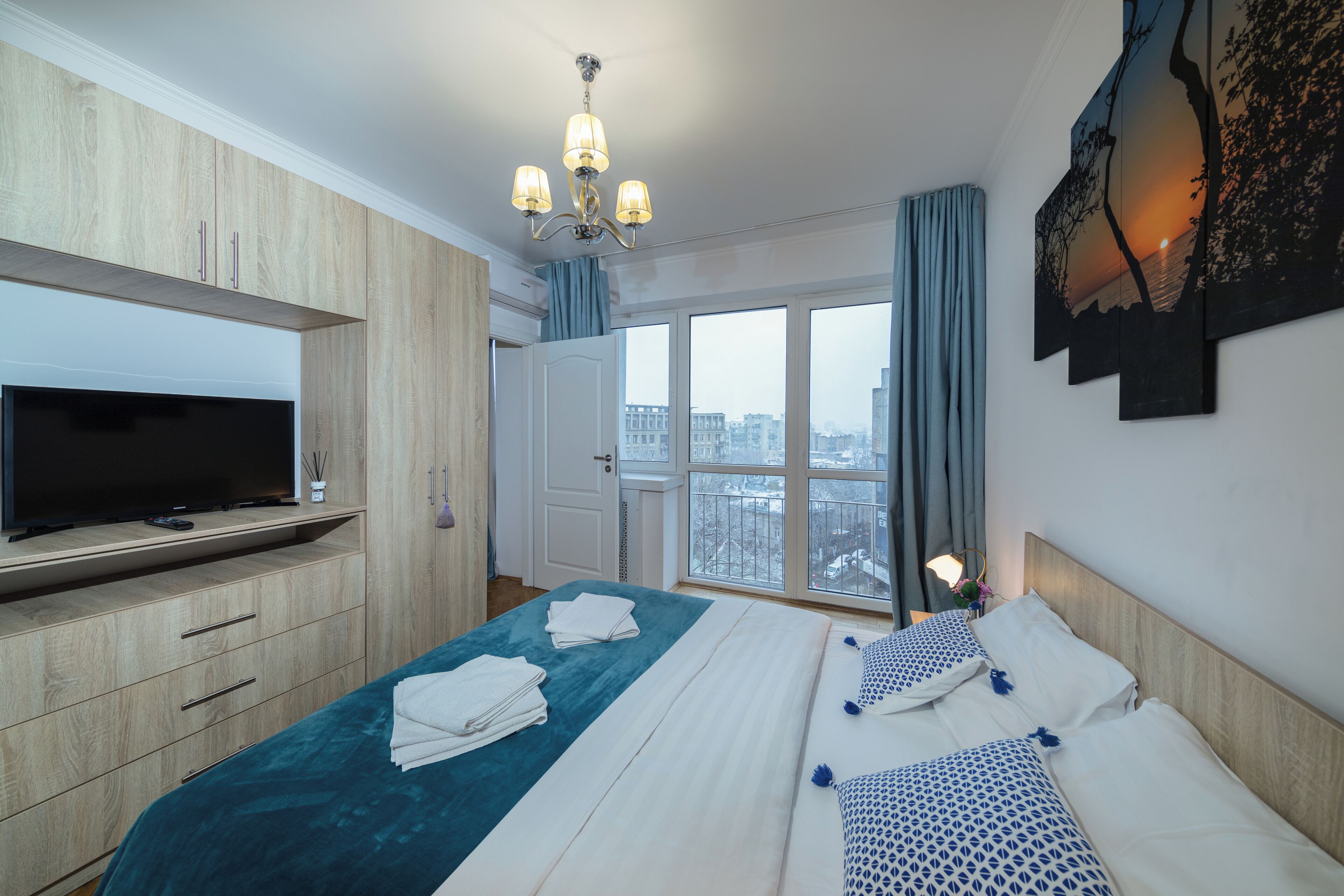 Ein Hotelzimmer mit Bett, Fernseher, großem Fenster und Blick auf die Stadt.
