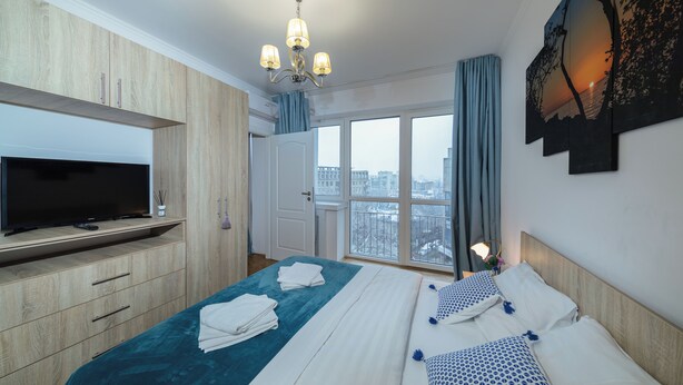 Una camera d'albergo con un letto, una televisione, un'ampia finestra e vista sulla città.