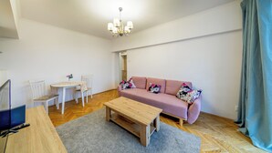 Un soggiorno con divano, tavolino, tavolo da pranzo con sedie e un lampadario.
