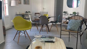 Moderni olohuone, jossa on pyöreä sohvapöytä, keltainen tuoli sekä ruokailutila, jossa on lasipöytä ja -tuolit.