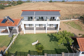Une maison moderne à deux étages, dotée d’un toit plat, de panneaux solaires, d’un balcon et d’une pelouse bien entretenue.