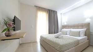 Une chambre d’hôtel moderne équipée d’un lit, d’un téléviseur fixé au mur, d’une table de chevet et d’une fenêtre avec des rideaux.