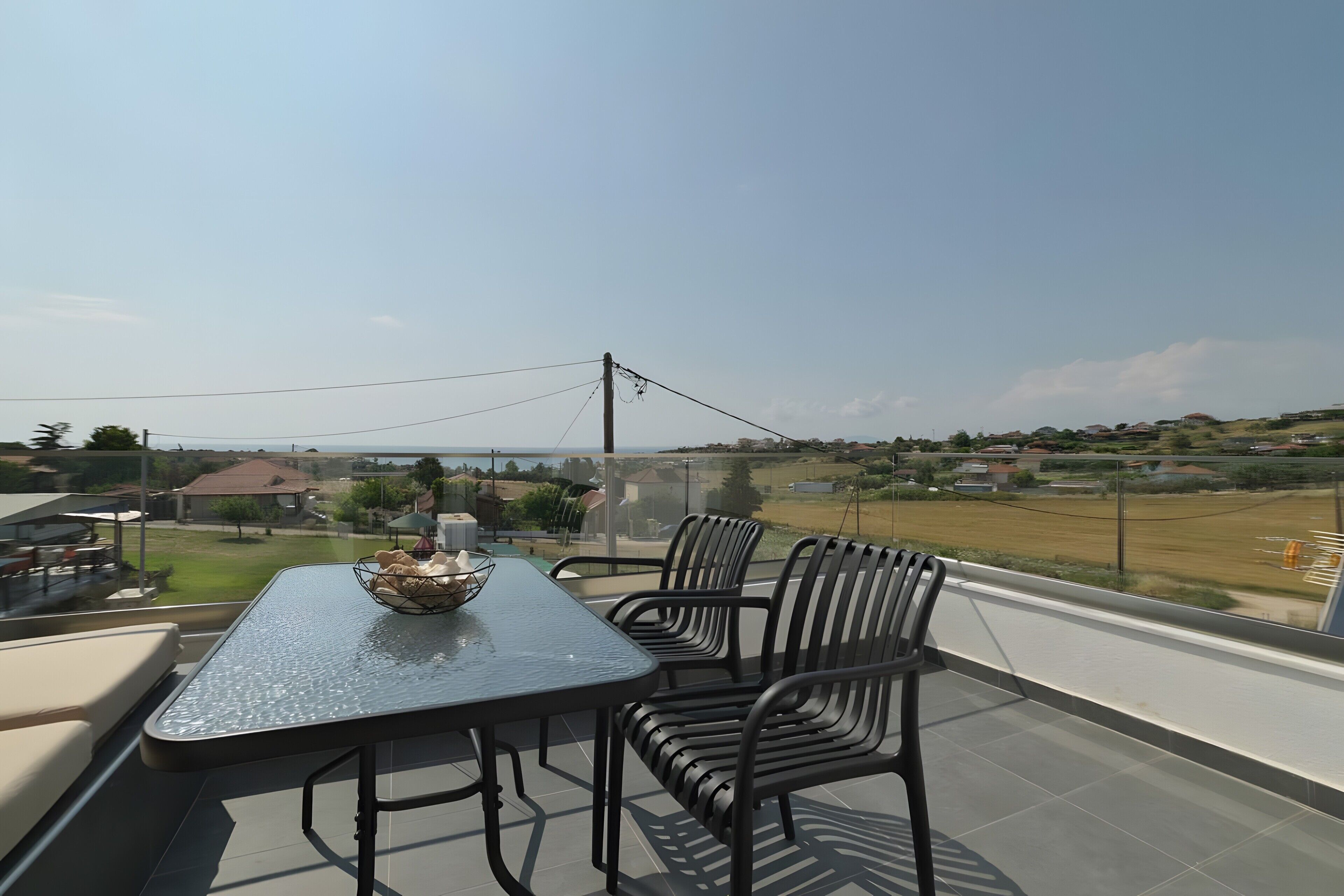 Un balcón con mesa y sillas, un bol de pan y vistas a una zona residencial.