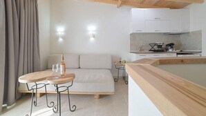 Une pièce moderne comprenant un canapé, une petite table en bois, un coin cuisine et un plafond en bois.