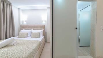 A hotel room with a bed, a bedside table, a wall-mounted light, and a sliding door leading to a bathroom.