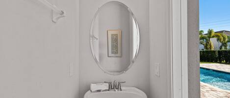 A bathroom with a white sink, a mirror, and a framed artwork above it.