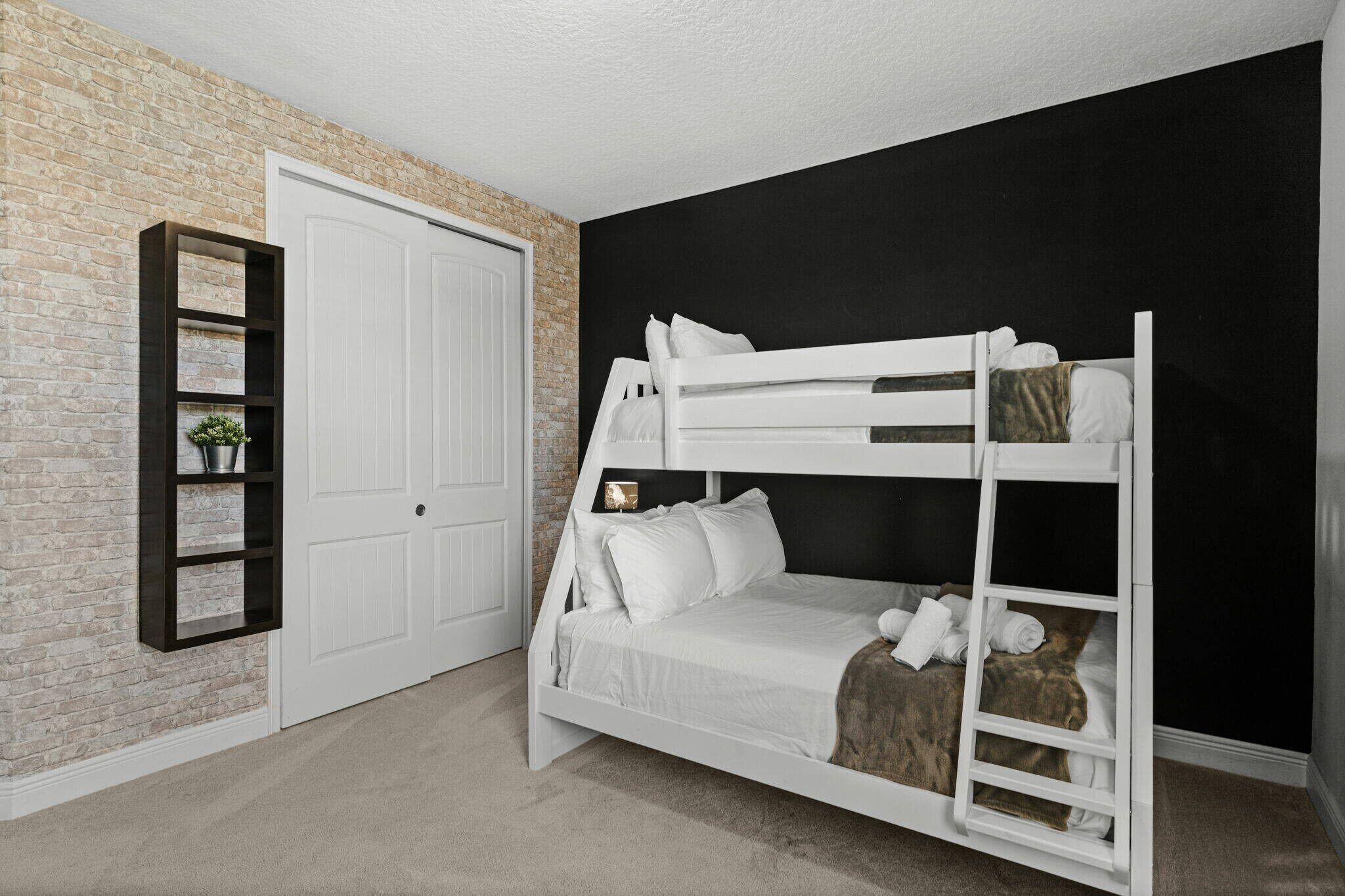 A bunk bed in a room with a brick wall and a black accent wall.
