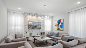 A modern living room with a sectional sofa, a glass coffee table, and a marble accent wall. - Last Minute Disney Getaway! Luxury Villa with Private Pool, Game Room & Themed Bedrooms. Book Now! #161617 (Orlando)