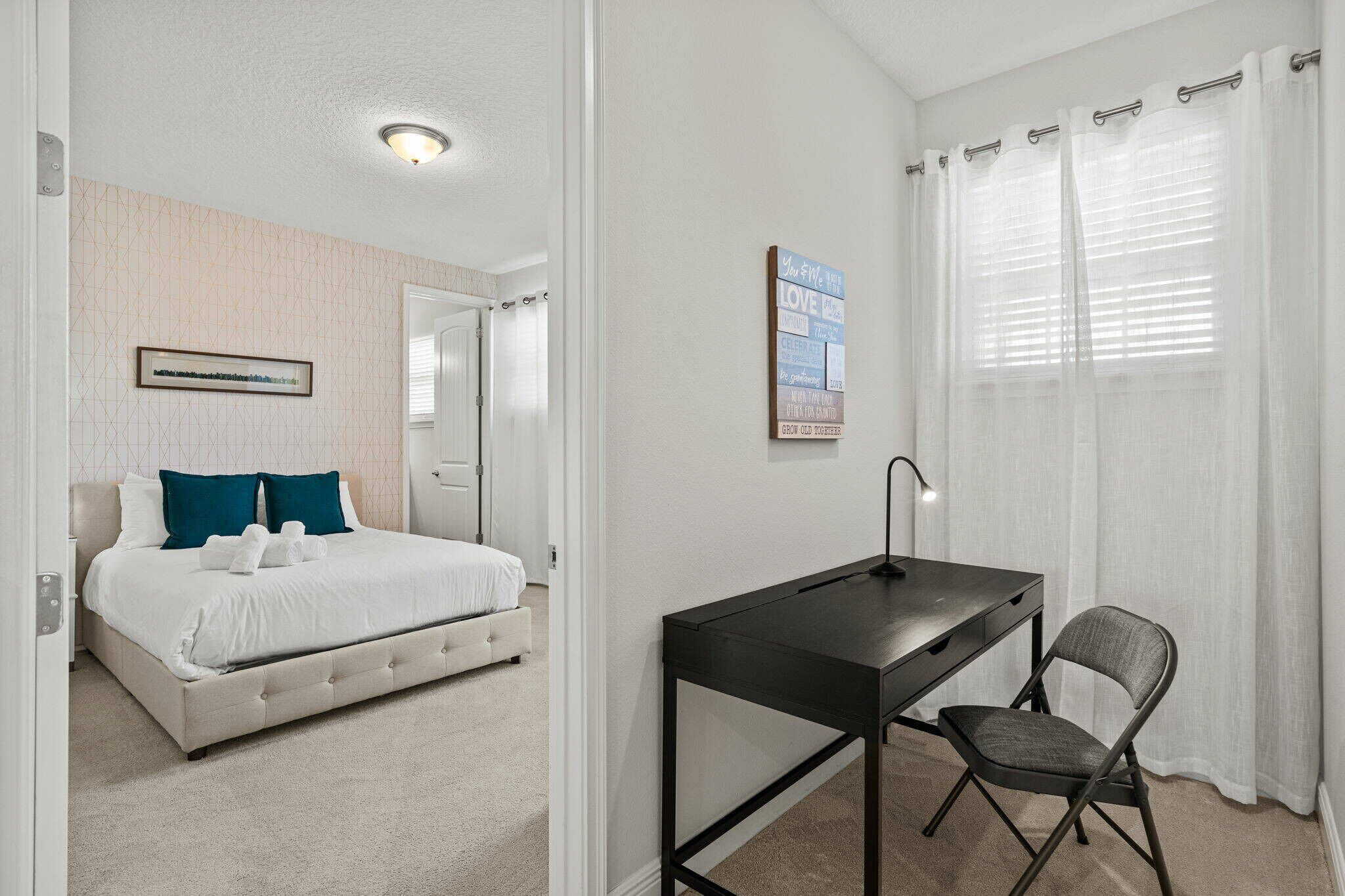 A bedroom with a bed, a desk, and a chair.