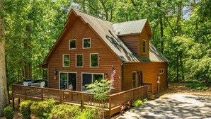 Une cabane en bois dotée d’une terrasse, entourée d’une forêt dense.