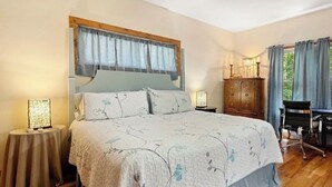 Une chambre à coucher avec un grand lit, un ventilateur de plafond, une armoire en bois et un bureau avec une chaise.